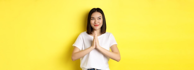 무료 사진 나마스테 기도 제스처에 손을 잡고 왼쪽을 보고 웃는 예쁜 아시아 여성은 expr에게 감사한다고 말합니다.