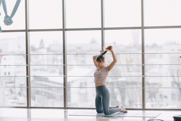 Foto gratuita ragazza abbastanza attraente che fa yoga in una stanza luminosa