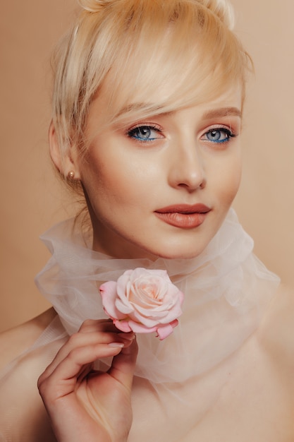 Pretty attractive girl with blond hair, fashion shooting, rose, simple background
