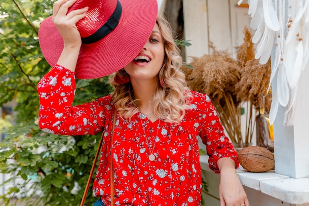 わらの赤い帽子とブラウスの夏のファッション衣装カフェでかなり魅力的なスタイリッシュな金髪の笑顔の女性