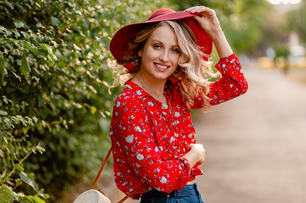 Pretty attractive stylish blond smiling woman in straw red hat and blouse summer fashion outfit