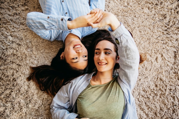 Pretty best friends holding hands on carpet