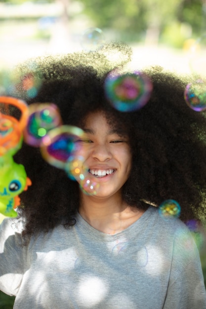 Pretty black teenage girl playing with soap bubbles