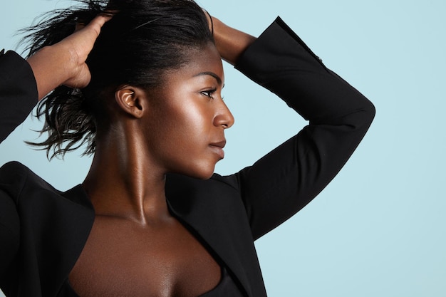 Free photo pretty black woman with ideal profile put the hands on a hair lifted up