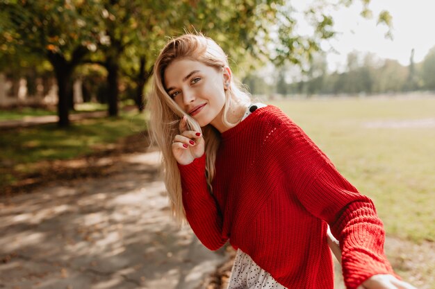 Pretty blonde looking playfully on the forest wall. Stunning woman feeling relaxed in the beautiful nature.