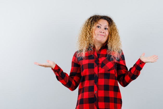 Free photo pretty blonde woman showing helpless gesture in checked shirt and looking confused , front view.