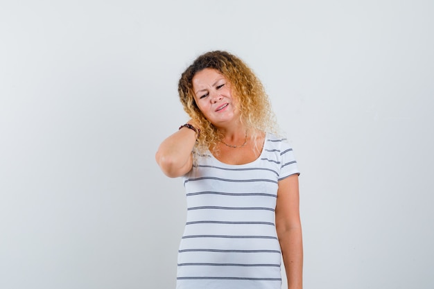 Pretty blonde woman in striped t-shirt suffering from neck pain and looking tired , front view.