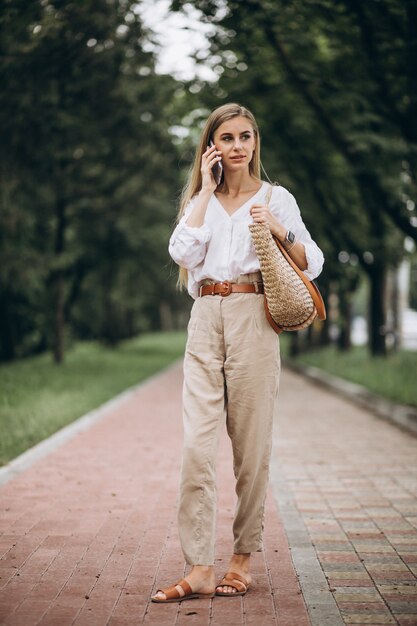 Pretty blonde woman using phone outside in park