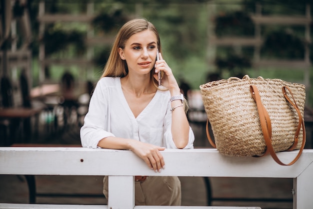 Pretty blonde woman using phone outside in park