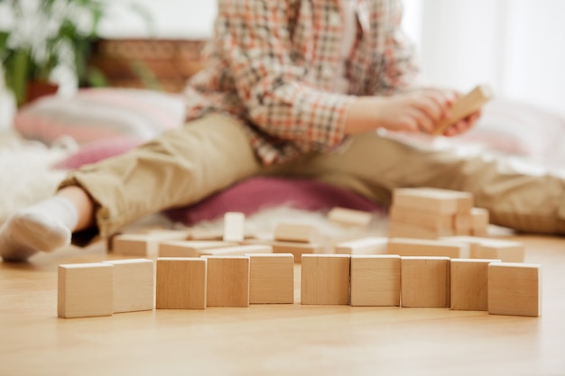 Pretty boy playing with wooden cubes at home