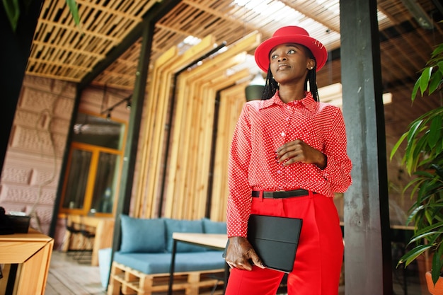 예쁜 머리띠 사업 아프리카 계 미국인 여성 밝은 보스 사람 친화적 인 사무실 빨간 셔츠 모자와 바지는 손에 태블릿을 들고