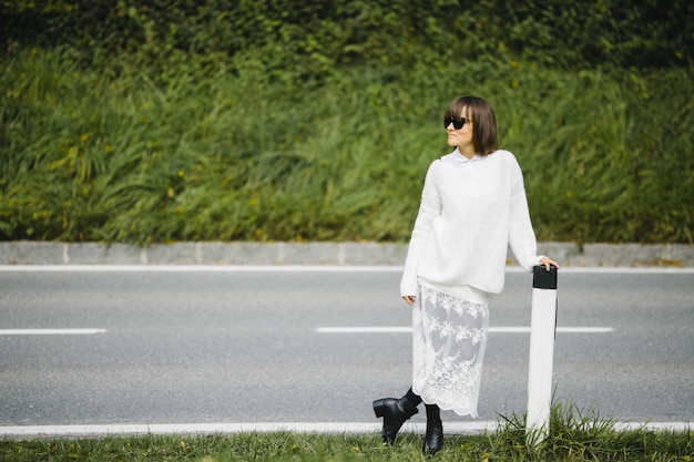 Free photo pretty brunette girl standing next to road