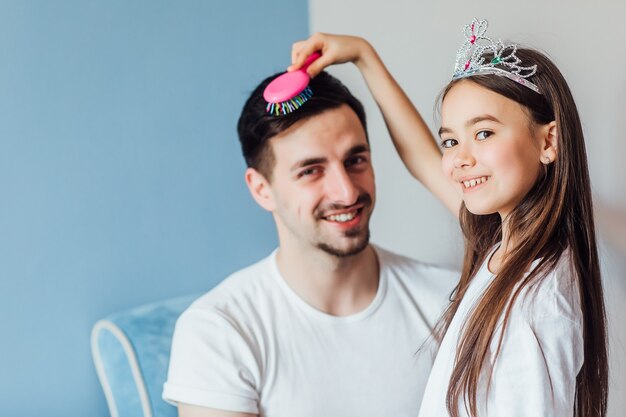 Pretty brunette princess girl is doing her father's hair