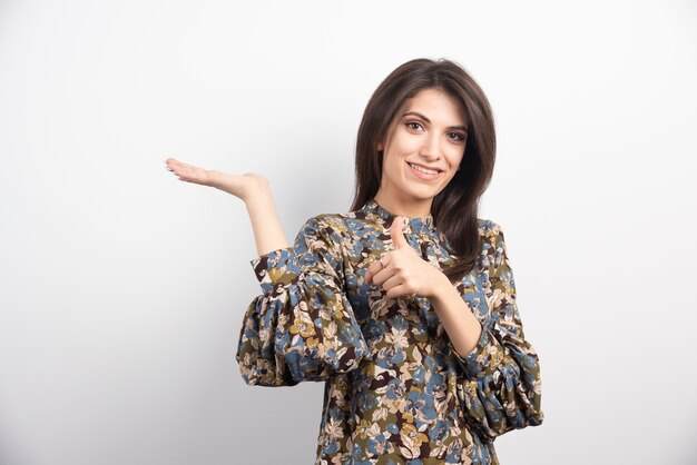 Pretty brunette woman giving thumbs up on a white background. 