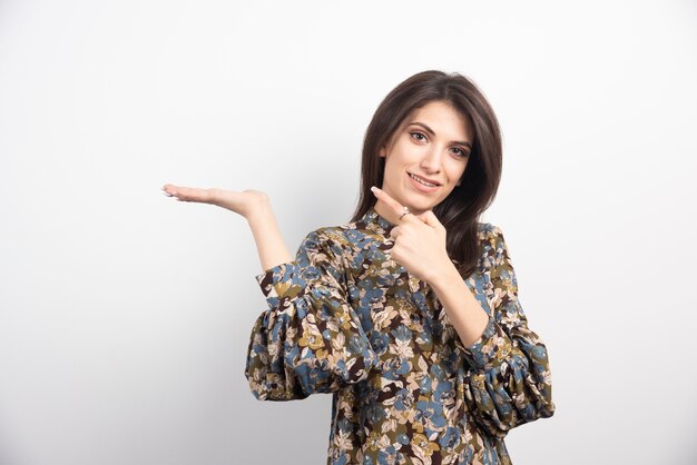 Pretty brunette woman pointing on a white background. 