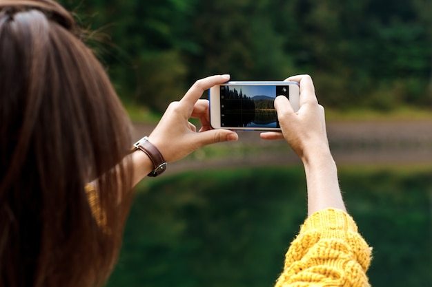 Pretty brunette woman taking photo of beautiful mountains view