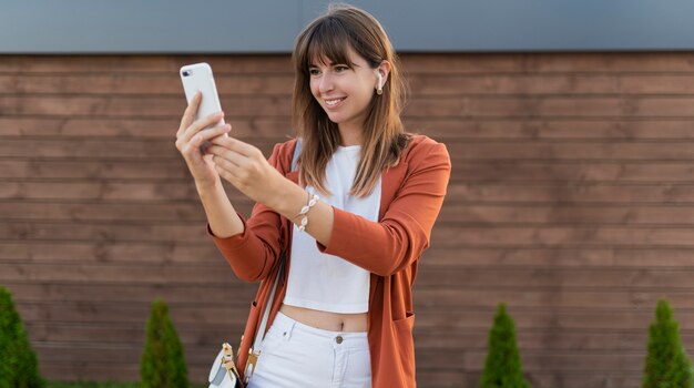 Pretty business woman using mobile phone and walking in city.