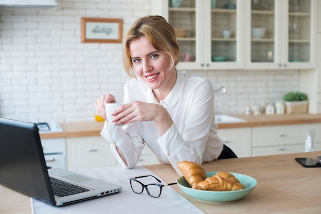 Pretty business woman with coffee using laptop