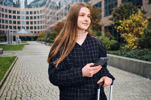 Pretty casual girl happily using cellphone on city street