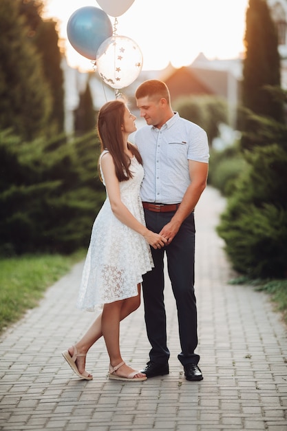 Pretty caucasian woman with long dark wavy hair in white dress hugs with beautiful man