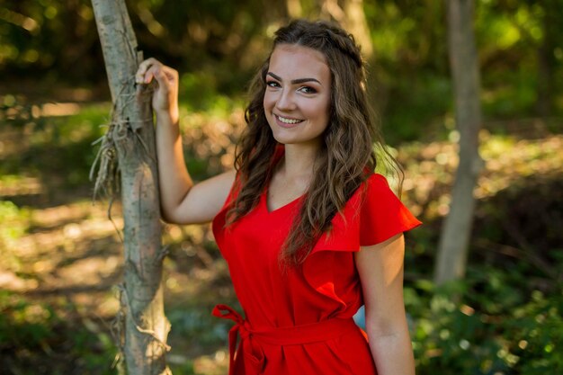 Pretty Caucasian woman with a red dress posing in the park