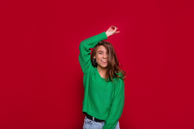 Pretty charming young woman dancing on red wall in winter outfit