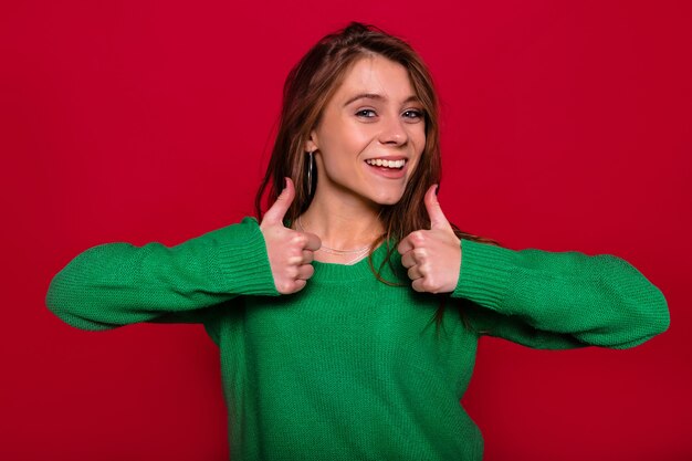 Pretty charming young woman on red wall in winter outfit