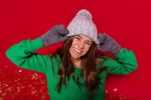 Pretty charming young woman on red wall in winter outfit