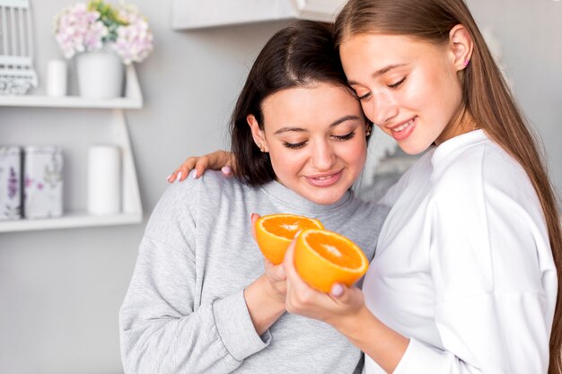 Красивая пара, держа половинки апельсина на кухне