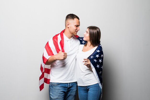 Красивая пара держит в руках флаг США, прикрывается, глядя друг на друга, изолированные на белом
