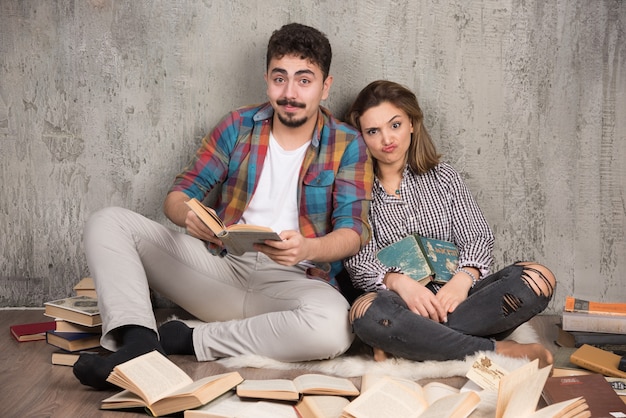 Foto gratuita bella coppia seduta sul pavimento con un sacco di libri