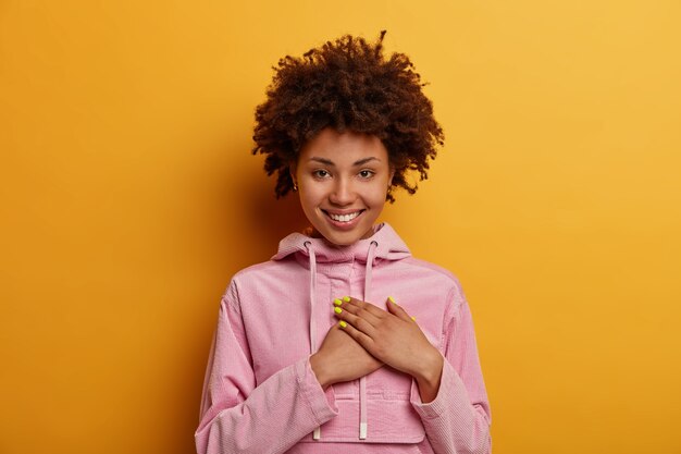 pretty curly haired woman presses palms to heart