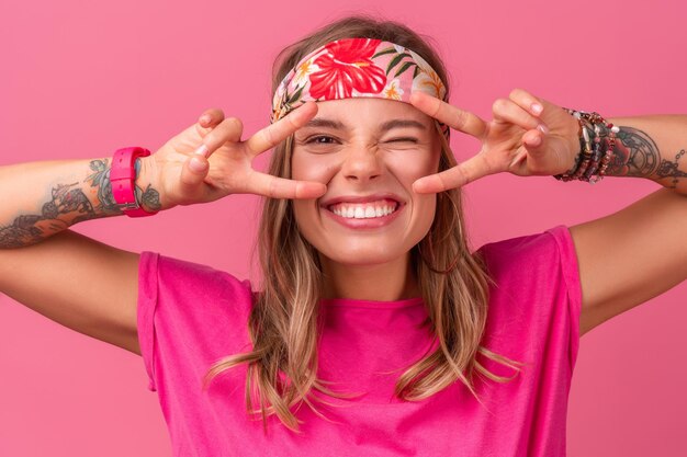 Donna sorridente abbastanza carina in camicia rosa accessori stile hippie boho sorridente divertimento emotivo in posa su sfondo rosa isolato umore positivo