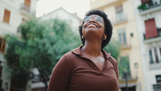 gを身に着けている通りに立っているかなり暗い髪のアフリカの女性