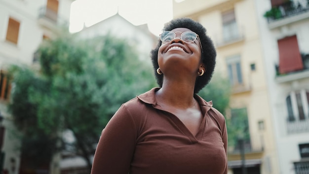 Pretty dark haired African woman standing on a street wearing g