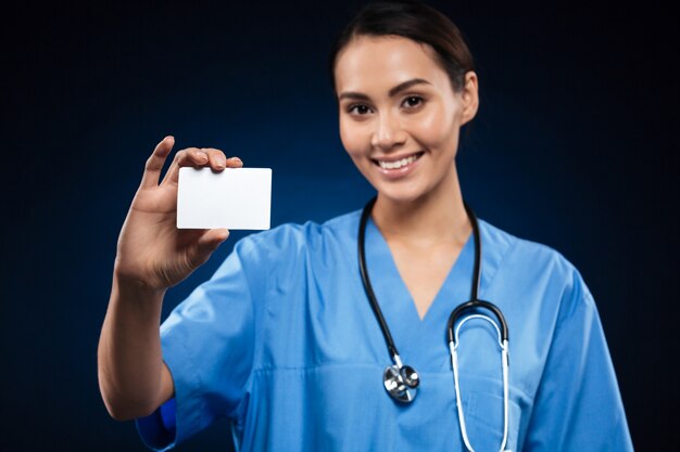 Pretty doctor showing blank id card or business card and smiling