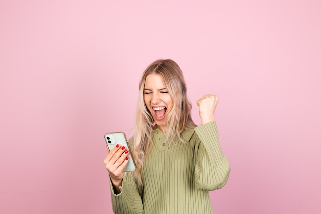 Donna abbastanza europea in maglione lavorato a maglia casual sulla parete rosa