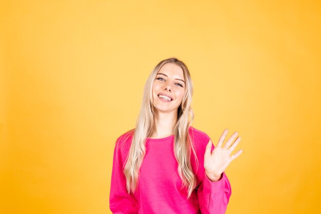 Pretty european woman in pink blouse on yellow wall