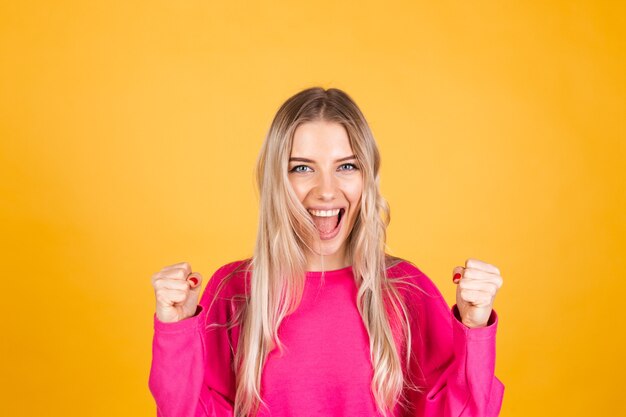 Pretty european woman in pink blouse on yellow wall