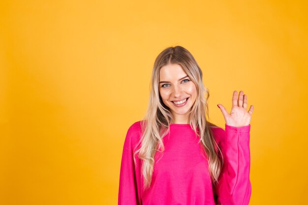 Pretty european woman in pink blouse on yellow wall