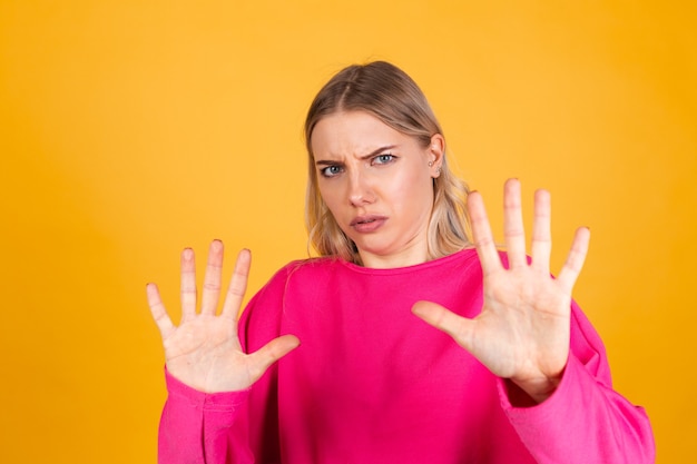 Pretty european woman in pink blouse on yellow wall