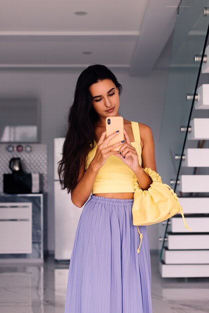 красивая модная блогерша в желтом топе и фиолетовых штанах