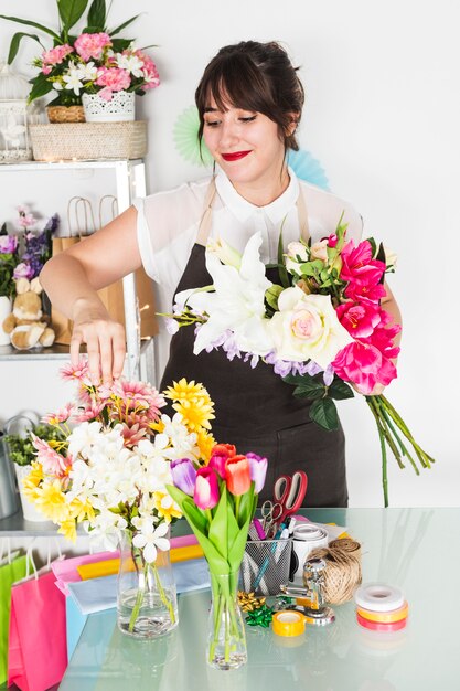 Pretty female florist arranging flowers in vase