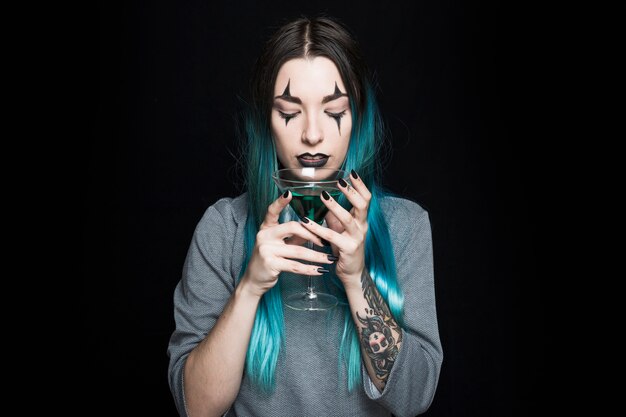 Pretty female holding wineglass with green beverage