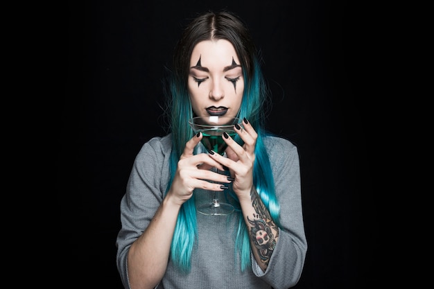 Pretty female holding wineglass with green beverage