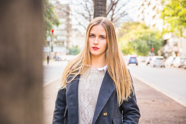 Pretty female looking at camera and standing on urban road