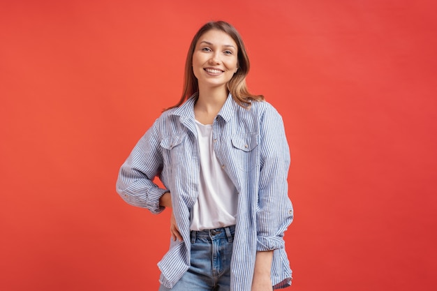Pretty female model posing with a smiling face expression on red wall