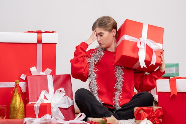 pretty female sitting around christmas presents feeling stressed on white