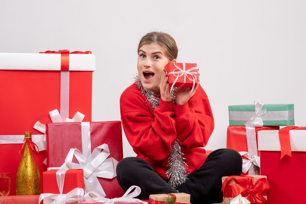 pretty female sitting around christmas presents on white