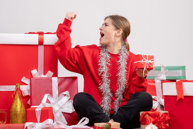 白のクリスマスプレゼントの周りに座っているきれいな女性